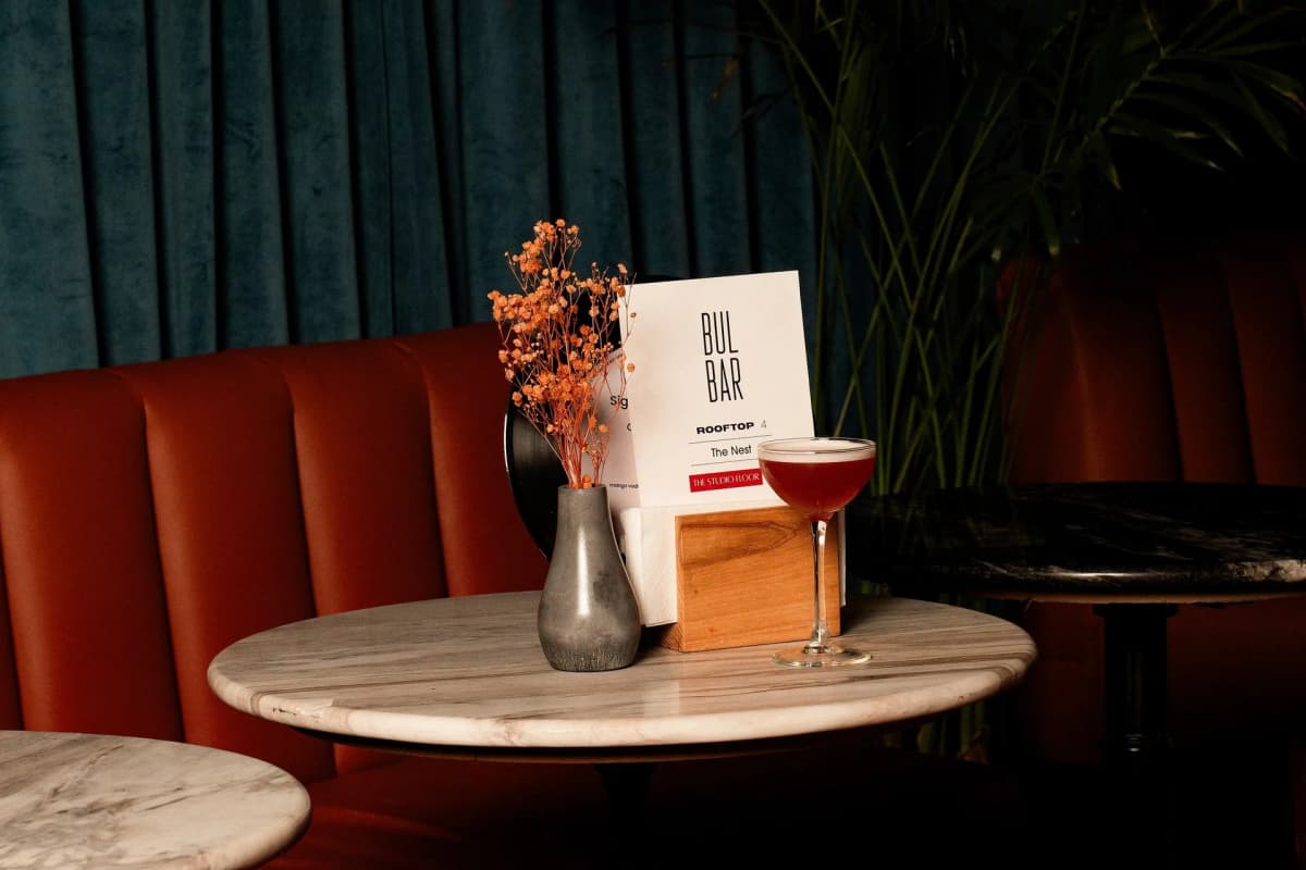 A cocktail beside the BUL BAR table card on marble