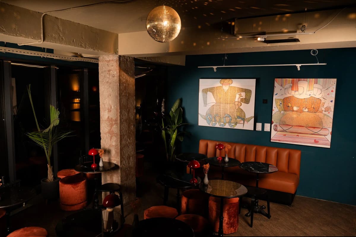 A mirror ball above the banquette and framed artwork on the teal wall